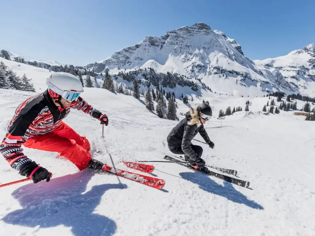 Zwei Skifahrer sausen die Piste hinunter in Warth-Schröcken