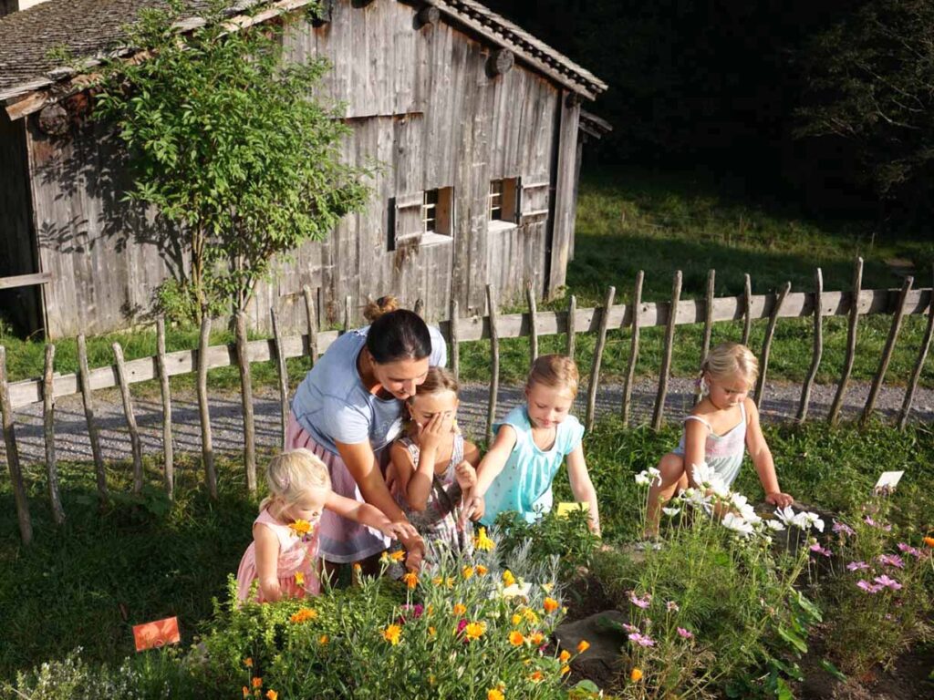 Vier Kinder und eine Frau im Kräutergarten im Bregenzerwald