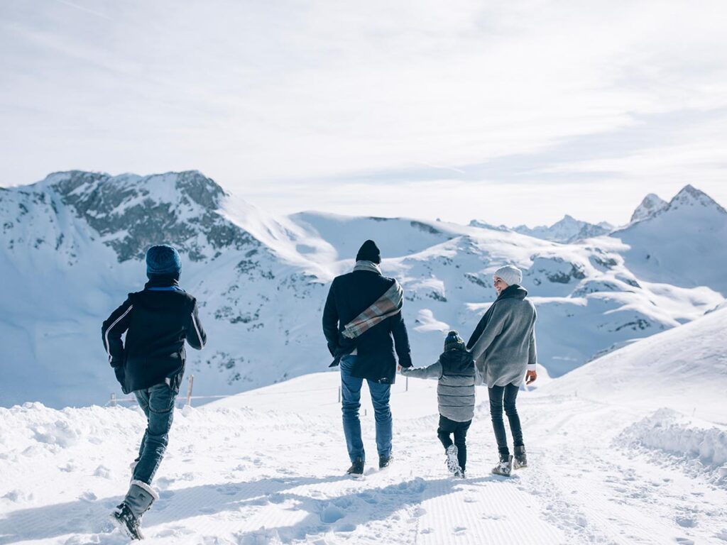 Familie mit Kinder beim Winterwandern in Lech, rundum verschneite Berge