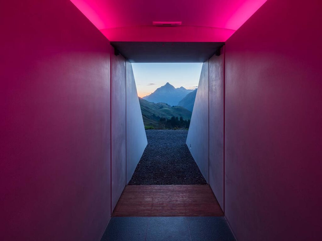 Ausgang des Projekts "Skypsace" des Künstlers James Turrell in Lech am Arlberg, pink beleuchteter Raum und Aussicht auf Bergkulisse.
