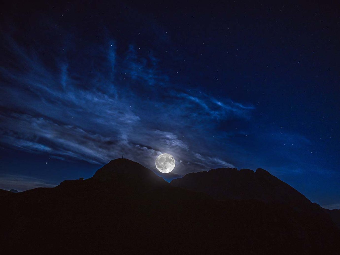 Berge im Dunkeln in der Nacht, Mond und Sterne scheinen auf Ortschaft bei der Laurentiusnacht