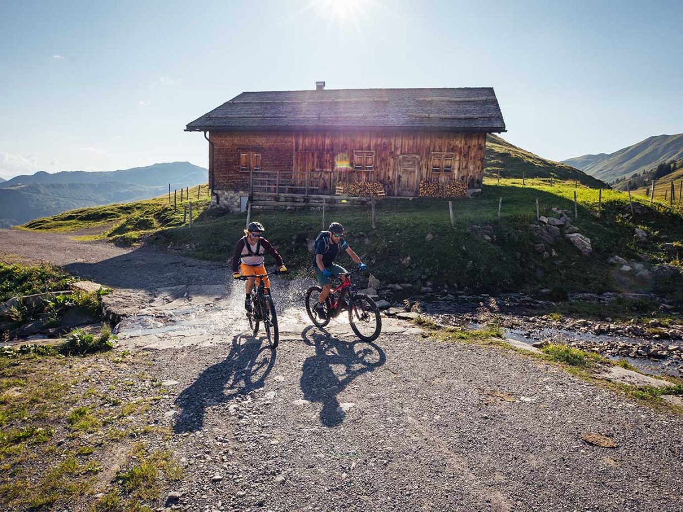 Zwei Radfahrer mit Mountainbikes und Hütte im Hintergrund