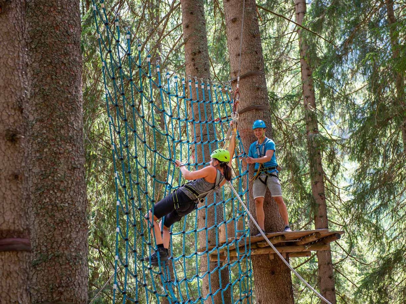 Zwei Erwachsene am Klettern auf Netz zwischen Bäumen in Damüls